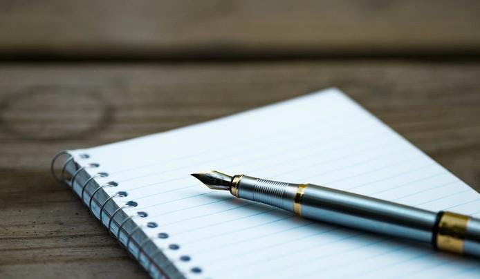 an image of a notebook and pen on a desk