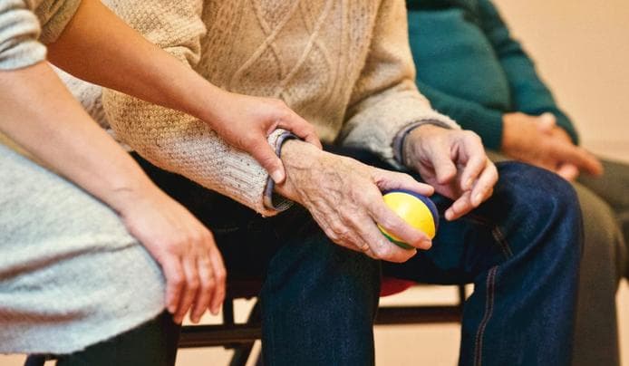 A person holding an elderly person hands