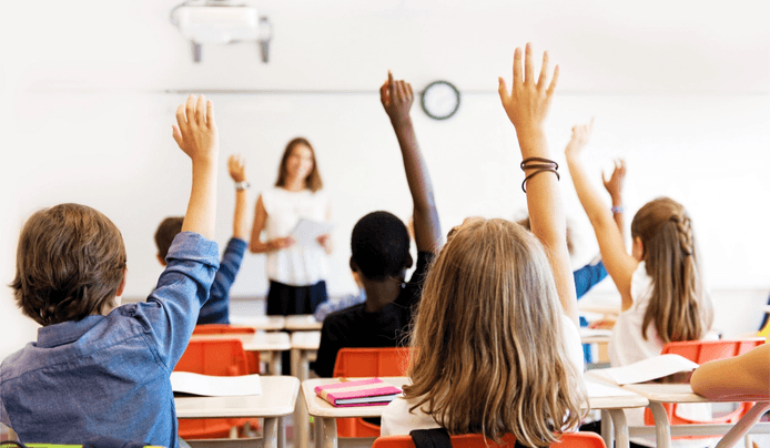 Kids raising hands to answer a question in the classroom