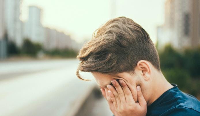 an image of a person covering his eyes from fatigue