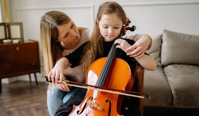 A music teacher teaching a young girl how to play an instrument
